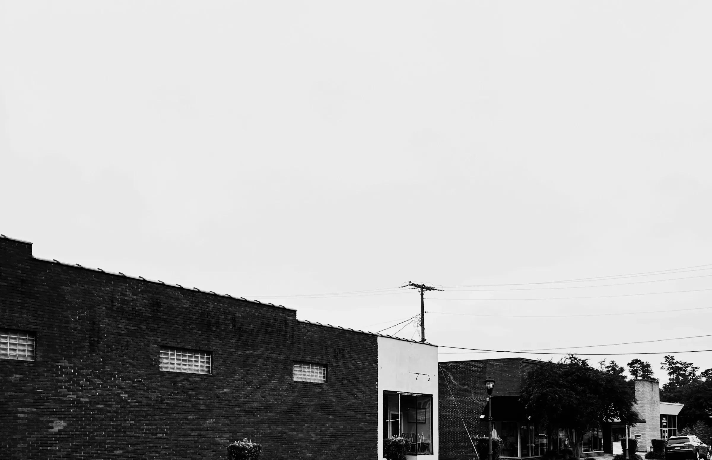 A blank brick flank and an empty sky, the street running away behind it.