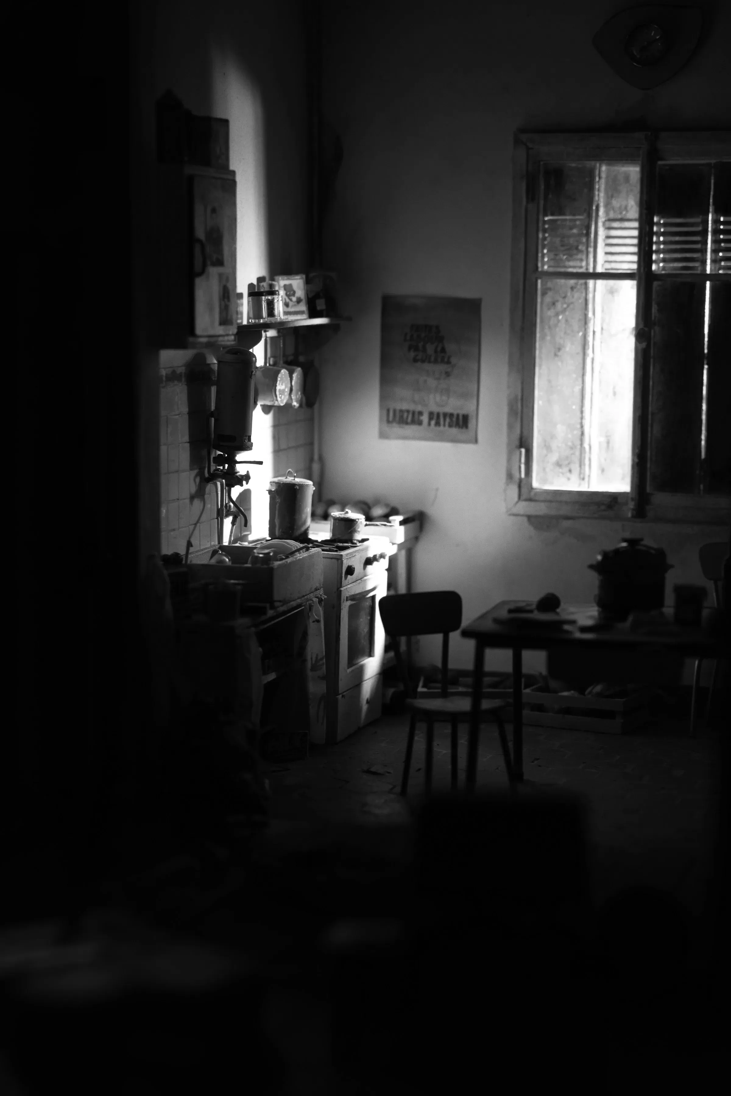 A lamp-lit kitchen, a poster on the wall and a pot left on the stove.