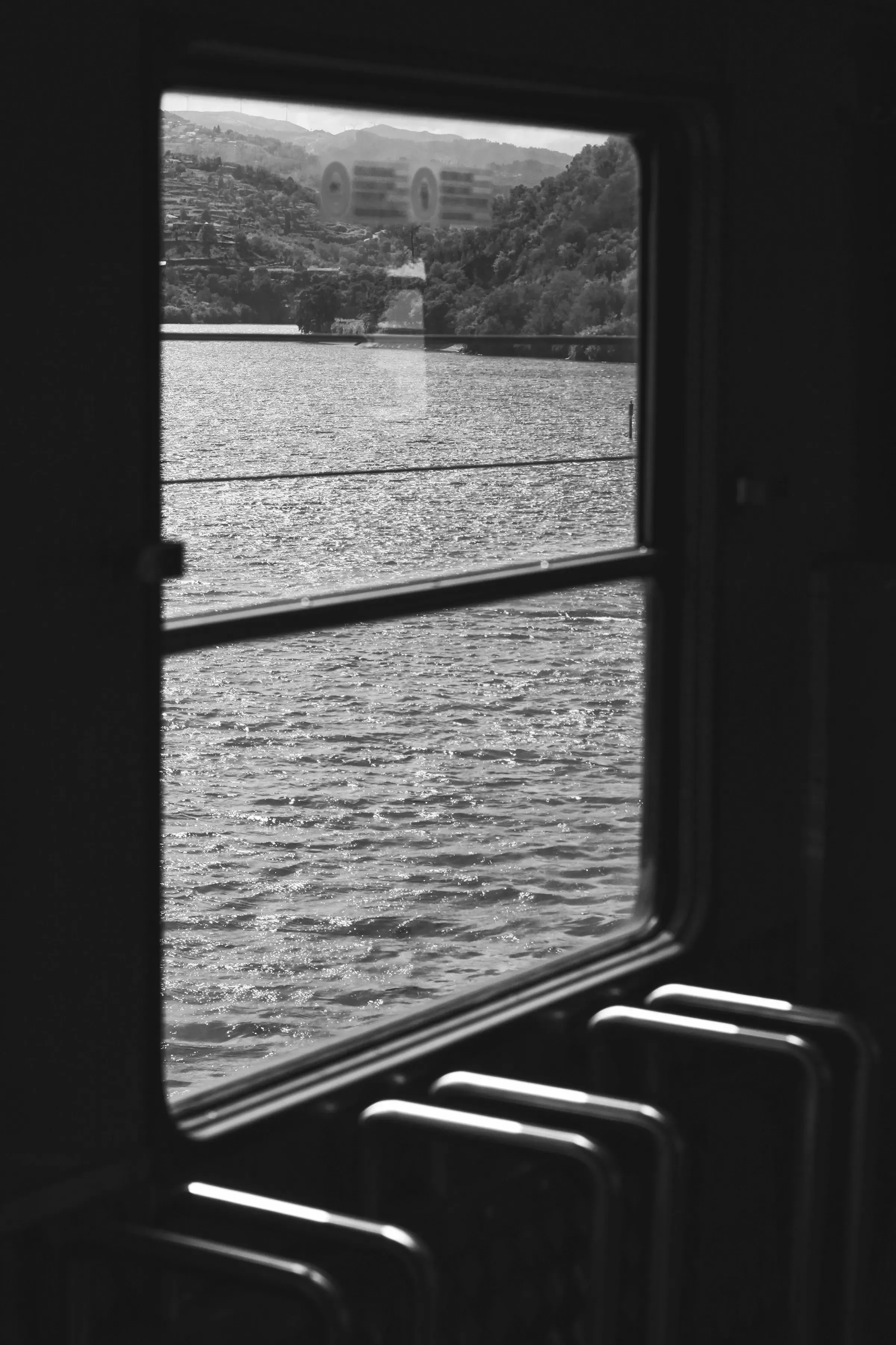 A landscape running past, framed by the dark window of a moving carriage.