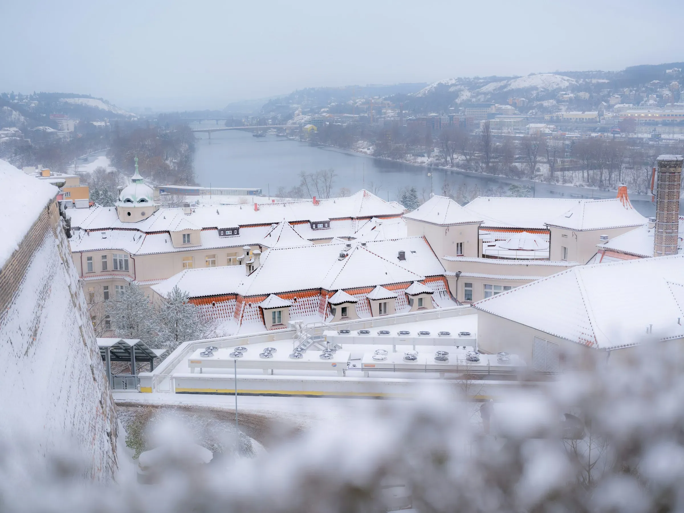 The river under snow, the road bridge in the distance, and the town stacked on the far bank.